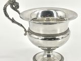 une coupe en argent ornée d'une poignée en forme de dragon, posée sur un socle