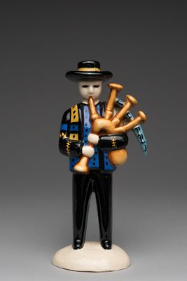 figurine représentant un homme jouant de la cornemuse et tenant une cornemuse