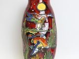 a red vase with a painting on it on a white surface