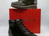 des chaussures pour homme dans une boîte rouge, accompagnées d'une paire de bottes vertes