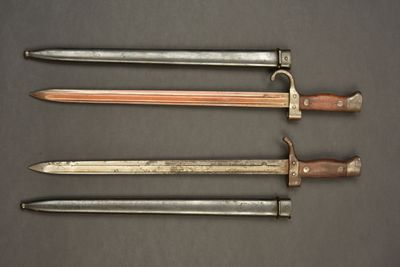 three old swords are lined up on a black surface