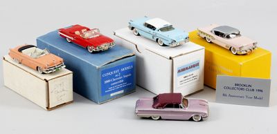 cinq petites voitures posées sur des cartons, sur une table
