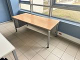 a desk in the corner of a room with a large window