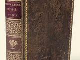 un vieux livre posé sur une table à côté d'un mur blanc