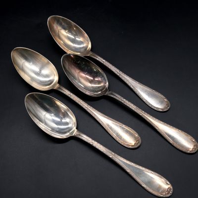 a set of four silver spoons on a black surface