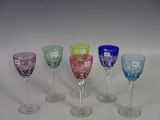 several different colored wine glasses are lined up on a white surface