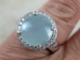 un gros plan de la main d'une personne tenant une bague sertie d'une pierre bleue
