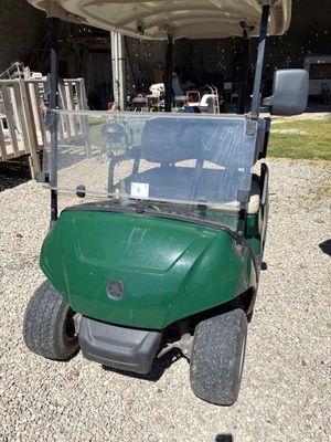 une voiturette de golf verte garée sur un parking en gravier