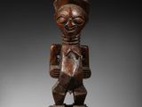 une statue en bois d'un homme avec un chapeau sur la tête