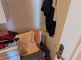 une chaise dans un coin d'un placard où sont suspendus des vêtements