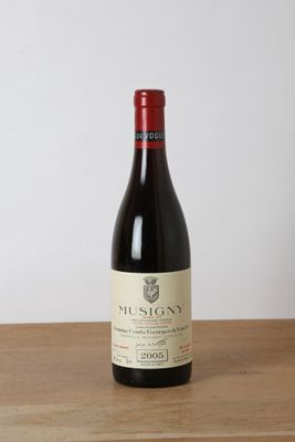 the bottle of red wine is sitting on a wooden table