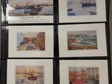 four framed watercolor paintings of boats on display in a black frame