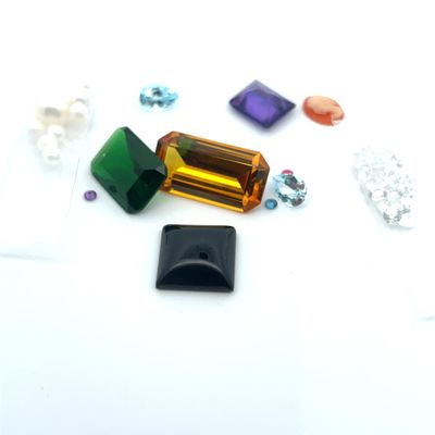 Plusieurs pierres précieuses de différentes couleurs sont dispersées sur une surface blanche.