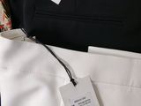 three pairs of pants with a price tag on them sitting on top of a bed