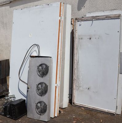 deux réfrigérateurs et un micro-ondes posés devant un immeuble