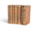 trois vieux livres sont empilés sur une surface blanche