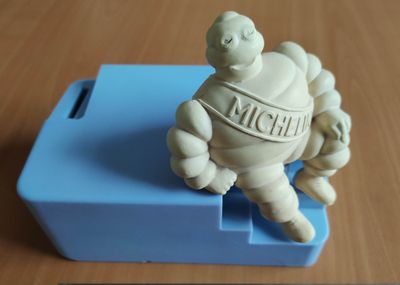 une petite figurine représentant un homme assis sur une boîte bleue