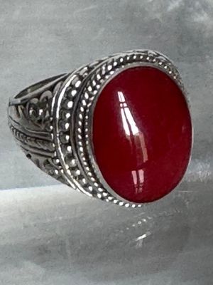 bague en argent sertie d'une pierre rouge sur un fond blanc