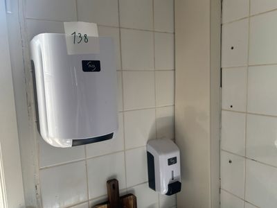 des toilettes avec un distributeur de papier dans un coin de la salle de bains