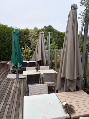 des tables et des chaises sur une terrasse équipée de parasols, par une journée nuageuse