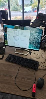 a desk with a computer, keyboard, mouse, and other items on it