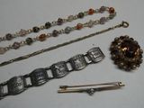 un bracelet, une broche, une épingle et d'autres bijoux posés sur une table