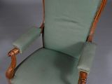 une chaise à l'ancienne avec une assise rembourrée verte et un piètement en bois