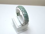 an image of a ring with green stones on a white surface