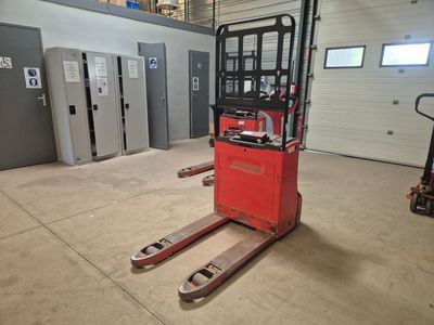 un chariot élévateur rouge dans un entrepôt dont les portes sont ouvertes