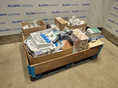 Des cartons de matériel médical sont empilés sur une palette devant un mur