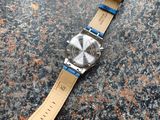 a close up of a watch on a stone surface with a blue strap