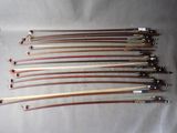 a group of six wooden and metal bows sitting on top of a white sheet
