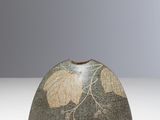 un petit vase orné d'un motif de feuilles