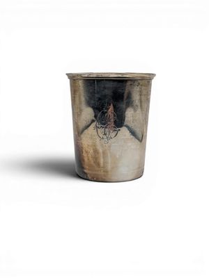 a silver cup with a design on it on a white surface