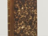 un vieux livre à la couverture marron posé sur une table blanche
