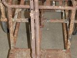 a rusted iron chair sitting on top of a metal stand