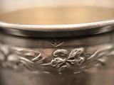 a silver cup with a flower design on it