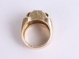 a gold ring with a stone in it on a white surface