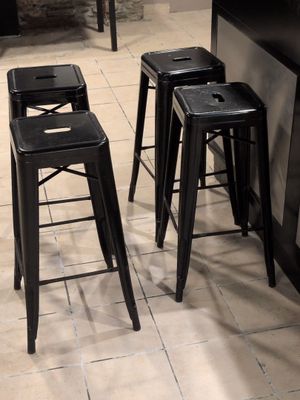 quatre tabourets noirs placés dans une cuisine, près d'un plan de travail