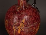 a red vase sitting on top of a wooden table