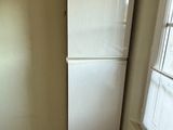 a white refrigerator in the corner of a room with a window