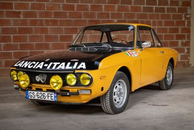 yellow and black car parked in front of a brick wall