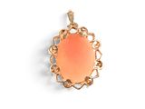 an image of a gold pendant with an orange stone in the center