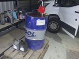 un fût bleu posé sur une palette à côté d'une camionnette blanche