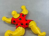 yellow and red stuffed animal laying on its back on a gray surface