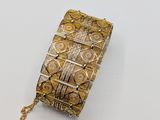 a close up of a gold and silver bracelet on a white surface