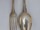 two silver spoons and a fork on a white surface