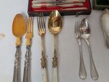 a lot of silverware on a table with a red case