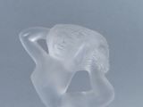 a glass figurine of a woman holding her hands behind her head