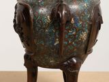 a bronze vase sitting on a wooden stand on a table